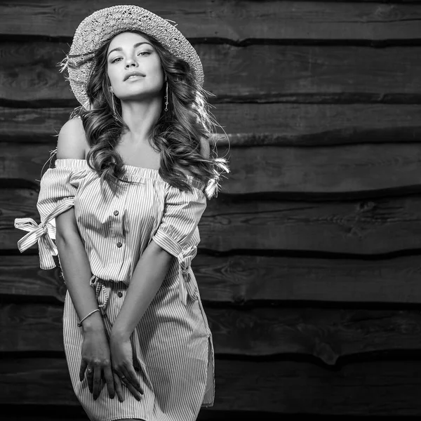 Retrato blanco y negro de una hermosa joven con sombrero clásico contra una vieja pared de madera . — Foto de Stock