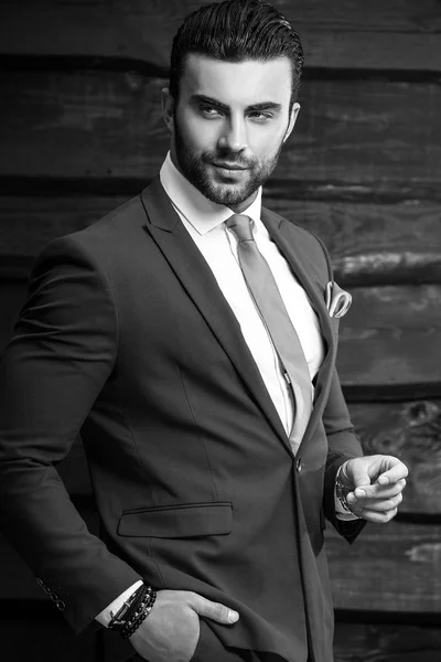 Retrato blanco y negro del hermoso hombre de moda en traje elegante sobre fondo de madera . —  Fotos de Stock