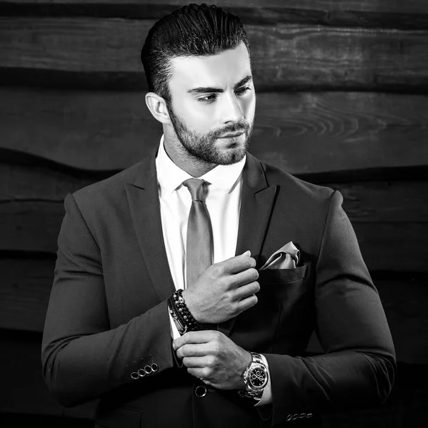 Retrato blanco y negro del hermoso hombre de moda en traje elegante sobre fondo de madera . — Foto de Stock