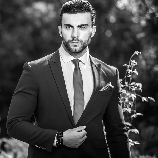 Schwarz-weißes Außenporträt eines eleganten gutaussehenden Mannes im klassischen Anzug. — Stockfoto