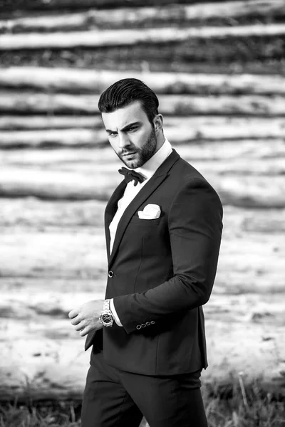 Black-white portrait of beautiful fashionable man in stylish suit against wooden background. — Stock Photo, Image