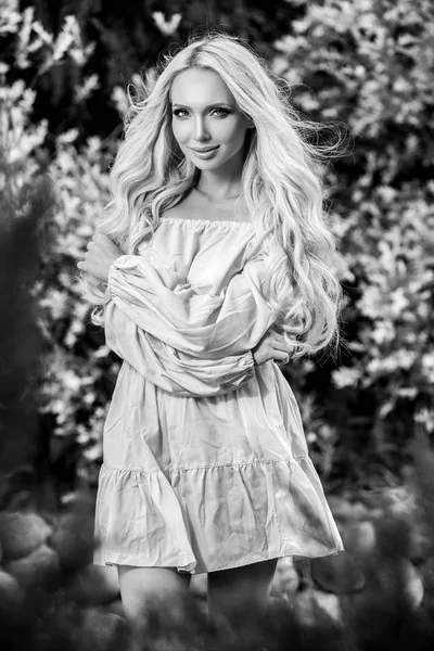 Retrato al aire libre blanco y negro de una hermosa mujer rubia joven en vestido elegante . — Foto de Stock