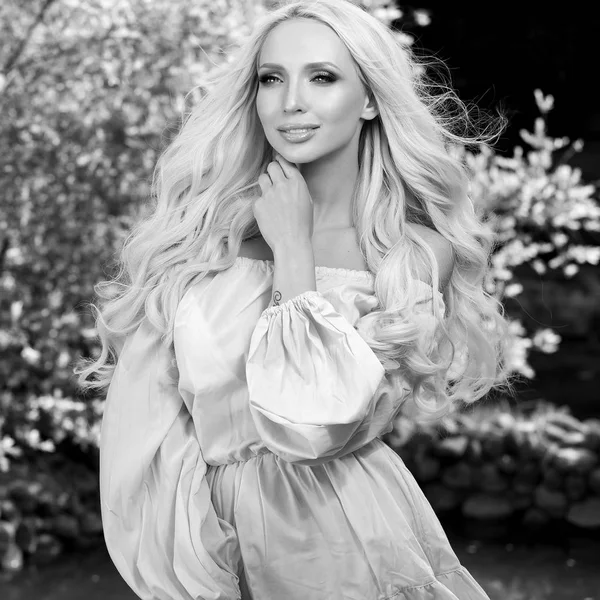 Svart-vit utomhus porträtt av vacker ung blond kvinna i snygg klänning. — Stockfoto