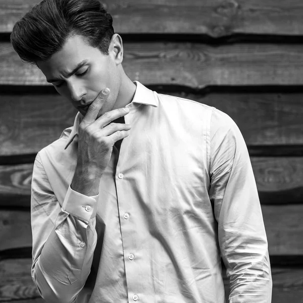 Retrato blanco y negro del joven guapo hombre de moda contra la pared de madera . — Foto de Stock