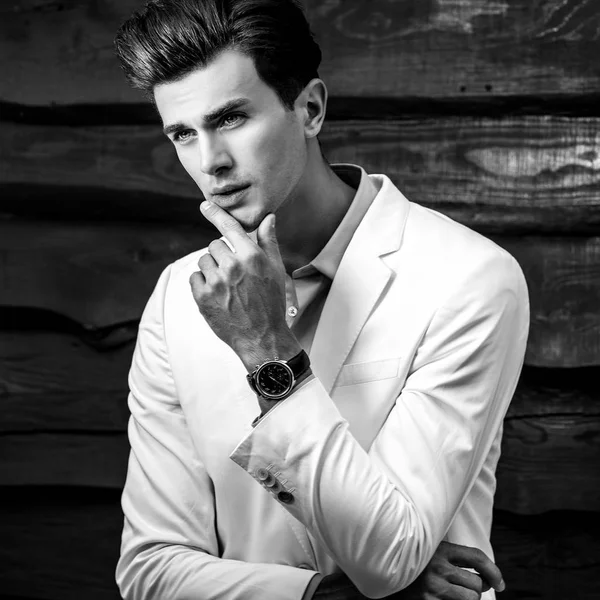 लकड़ी की दीवार के खिलाफ सफेद सूट में युवा सुंदर फैशनेबल आदमी का काला सफेद चित्र — स्टॉक फ़ोटो, इमेज