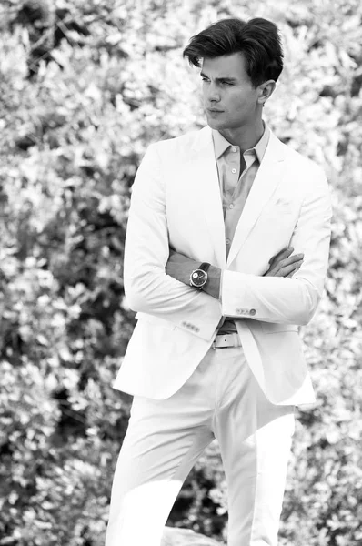 Retrato blanco y negro del joven guapo hombre de moda en traje blanco contra el fondo de la naturaleza —  Fotos de Stock