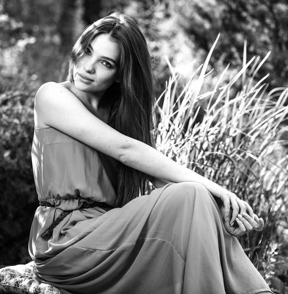 Черно-белый открытый портрет красивой эмоциональной молодой брюнетки в стильном платье — стоковое фото