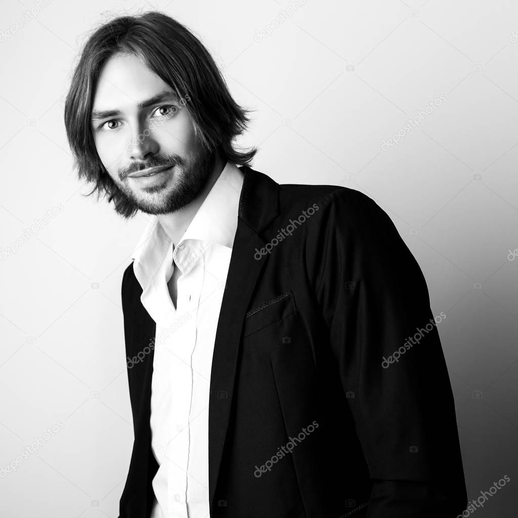 Black-white portrait of young handsome long hair man against studio background.