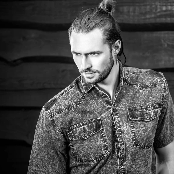 Retrato blanco y negro del joven guapo hombre de pelo largo sobre fondo de madera . — Foto de Stock