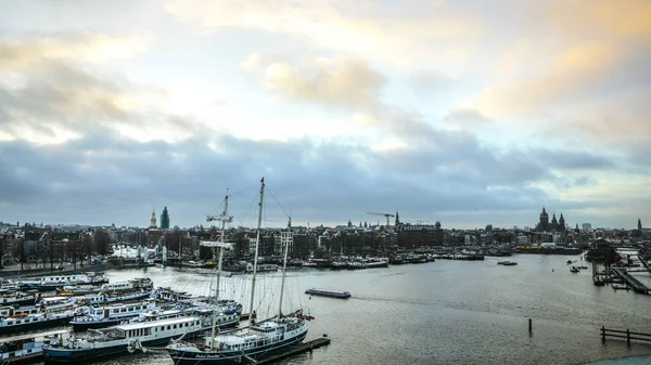 AMSTERDAM, PAÍSES BAJOS - 02 DE ENERO DE 2017: Barcos en el agua en la hermosa puesta de sol por la noche. Enero 02, 2017 en Amsterdam - Holanda . — Foto de Stock