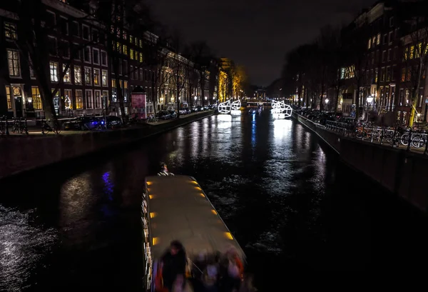 Amsterdam, Nederland - 11 januari 2017: Prachtige nacht stad Amsterdamse grachten met bewegende reizigerskilometers boot. Amsterdam - Nederland, 11 januari 2017. — Stockfoto