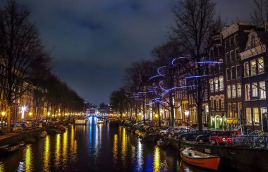 Amsterdam, Hollanda - 12 Ocak 2017: Cruise tekneler acele gece kanallarında. Amsterdam içinde ışık Festivali ışık teçhizatları gece Kanallar üzerinde. 12 Ocak 2017 yılında Amsterdam - Hollanda