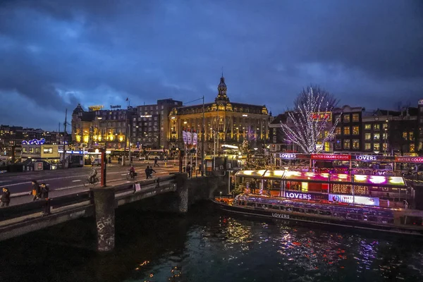 AMSTERDAM, PAÍSES BAJOS - 12 DE ENERO DE 2017: Hermosos canales nocturnos de la ciudad de Ámsterdam con barco pasajero en movimiento. 12 de enero de 2017 en Amsterdam - Países Bajos . —  Fotos de Stock