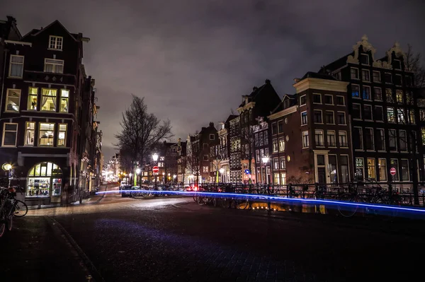 AMSTERDAM, PAÍSES BAJOS - 09 DE ENERO DE 2017: Amsterdam calles nocturnas de la ciudad con diferentes tipos de transporte en movimiento y siluetas de transeúntes. enero 09, 2017 en Amsterdam - Países Bajos — Foto de Stock