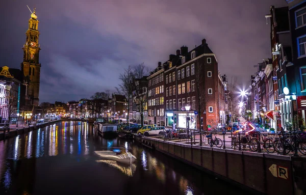 AMSTERDAM, PAÍSES BAJOS - 12 DE ENERO DE 2017: Hermosos canales nocturnos de la ciudad de Ámsterdam con barco pasajero en movimiento. 12 de enero de 2017 en Amsterdam - Países Bajos . — Foto de Stock