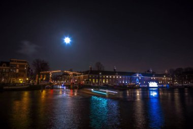 Amsterdam, Hollanda - 12 Ocak 2017: Cruise tekneler acele gece kanallarında. Dolunay Amsterdam ışık Festivali içinde ışık Installations gece Kanallar üzerinde. Amsterdam - Hollanda