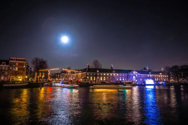 Amsterdam, Hollanda - 12 Ocak 2017: Cruise tekneler acele gece kanallarında. Dolunay Amsterdam ışık Festivali içinde ışık Installations gece Kanallar üzerinde. Amsterdam - Hollanda