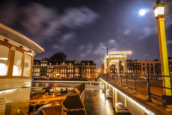 Amsterdam, Nederland - 12 januari 2017: Oude houten Nederlandse brug bij nachttijd tegen rush wolken op 12 januari 2017 in Amsterdam - Nederland. — Stockfoto