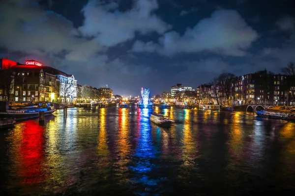 AMSTERDÃO, PAÍSES BAIXOS - JANEIRO 12, 2017: Belos canais noturnos da cidade de Amsterdã com barco de passageiros em movimento. 12 de janeiro de 2017 em Amsterdam - Países Baixos . — Fotografia de Stock