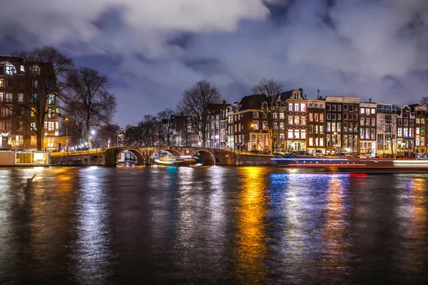 Amsterdam, Nederland - 12 januari 2017: Prachtige nacht stad Amsterdamse grachten met bewegende reizigerskilometers boot. Amsterdam - Nederland, 12 januari 2017. — Stockfoto