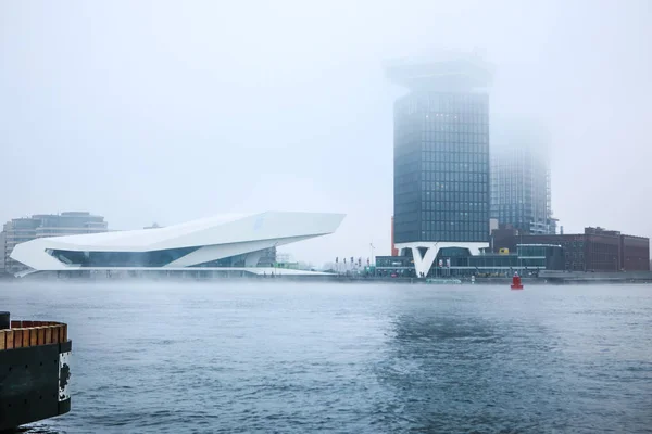 Widok ogólny kanał miasta, w pobliżu molo Amsterdam Central station w mglisty dzień. — Zdjęcie stockowe