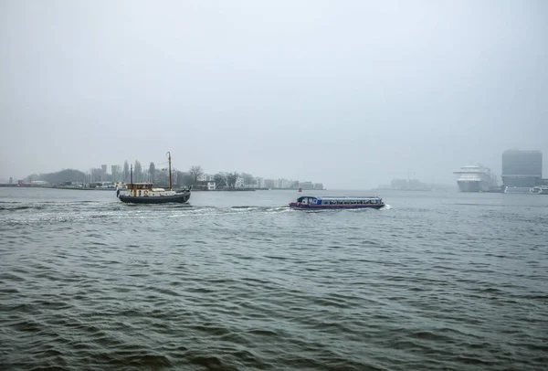 Sisli gün Amsterdam Merkez İstasyonu pier yakınındaki şehir Kanal genel görünümü. — Stok fotoğraf