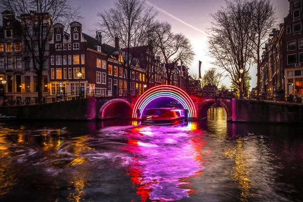 AMSTERDAM, PAÍSES BAJOS - 10 DE ENERO DE 2017: Los cruceros corren por los canales nocturnos. Instalaciones de luz en los canales nocturnos de Ámsterdam dentro del Festival de la Luz. 10 de enero de 2017 en Amsterdam - Países Bajos . — Foto de Stock