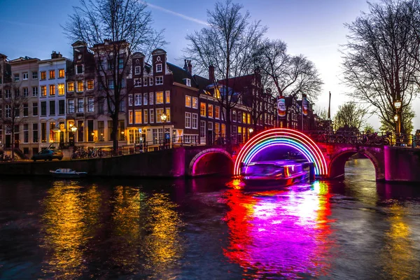 AMSTERDAM, PAÍSES BAJOS - 10 DE ENERO DE 2017: Los cruceros corren por los canales nocturnos. Instalaciones de luz en los canales nocturnos de Ámsterdam dentro del Festival de la Luz. 10 de enero de 2017 en Amsterdam - Países Bajos . — Foto de Stock