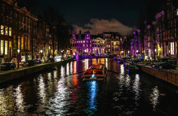 AMSTERDAM, PAYS-BAS - 11 JANVIER 2017 : Beaux canaux nocturnes d'Amsterdam avec bateau de passagers en mouvement. 11 janvier 2017 à Amsterdam - Pays-Bas . — Photo