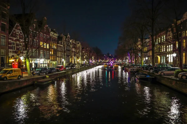 AMSTERDÃO, PAÍSES BAIXOS - JANEIRO 11, 2017: Belos canais noturnos da cidade de Amsterdã com barco de passageiros em movimento. 11 de janeiro de 2017 em Amsterdam - Países Baixos . — Fotografia de Stock