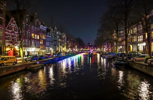 AMSTERDAM, PAÍSES BAJOS - 11 DE ENERO DE 2017: Hermosos canales nocturnos de la ciudad de Ámsterdam con barco pasajero en movimiento. 11 de enero de 2017 en Amsterdam - Países Bajos . —  Fotos de Stock