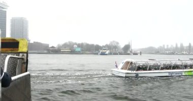 Amsterdam, Hollanda - 02 Ocak 2017: Tekneler sisli günde Merkez İstasyonu pier yakınındaki şehir kanalında. 4k Video. 02 Ocak 2017 yılında Amsterdam - Hollanda.