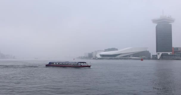 Amsterdam, Nederländerna - 02 januari 2017: Båtar på staden kanal nära piren i Central station i dimmig dag. 4k Video. 02 januari 2017 i Amsterdam - Nederländerna. — Stockvideo