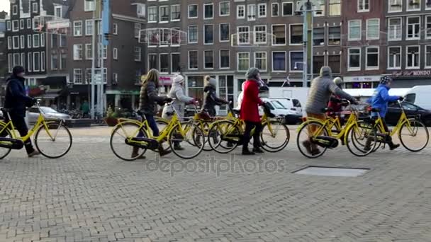 AMSTERDAM, NETHERLANDS - JANUARY 04, 2017: Group of tourists moving with rented yellow bicycles in Amsterdam city. Slow Motion Video. January 04, 2017 in Amsterdam - Netherlands. — Stock Video