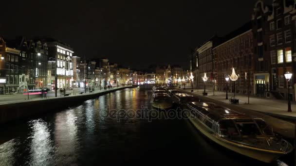 アムステルダムの運河の夜のアムステルダム, オランダ - 2017 年 1 月 6 日: クルーズ船ラッシュ。時間の経過。2017 年 1 月 6 日アムステルダム - オランダ. — ストック動画