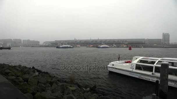 Amsterdam, Nederländerna - 02 januari 2017: Amsterdams centralstation i dimmig dag. De allmänna liggande vy av staden vallen med rush båtar. Tid förflutit. 02 januari 2017 i Amsterdam - Nederländerna. — Stockvideo