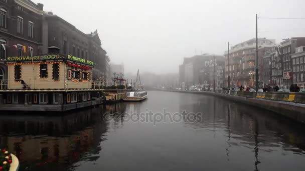АМСТЕРДАМ, НИДЕРЛАНДЫ - 02 ЯНВАРЯ 2017: Круизное судно по каналам Амстердама в туманный вечер. Время покажет. 2 января 2017 года в Амстердаме - Нидерланды . — стоковое видео