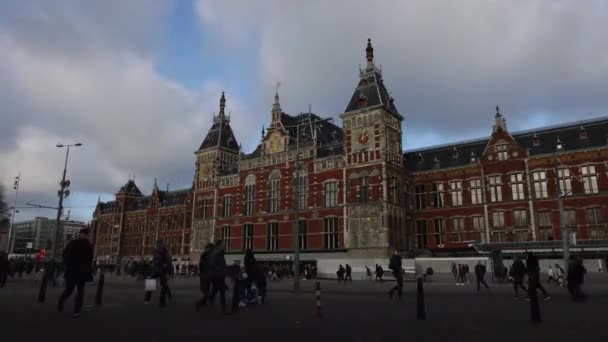 Amsterdam, Nederländerna - 02 januari 2017: Amsterdam centralstation framsidan med rörliga personer och spårvagnar. Tid förflutit. 02 januari 2017 i Amsterdam - Nederländerna. — Stockvideo