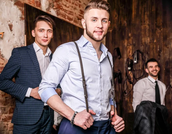 Tres jóvenes amigos positivos elegantes posan en el interior de la barbería . —  Fotos de Stock