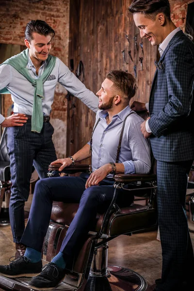 Drie jonge elegante positieve vrienden pose in interieur van barbershop. — Stockfoto