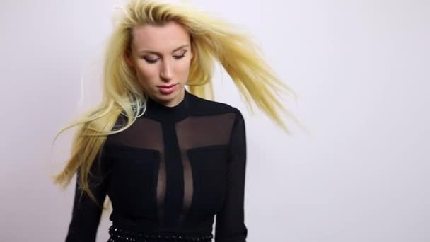 Vacker sexig blond kvinna i svart klänning posera mot studio bakgrund. Slow Motion Footage. — Stockvideo