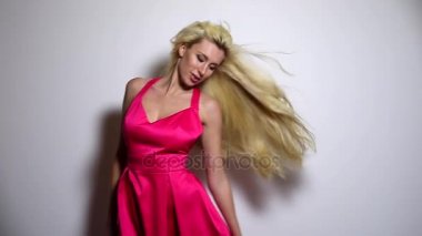 Pembe elbiseli güzel seksi kadın poz studio arka planı. Ağır çekim görüntüleri.