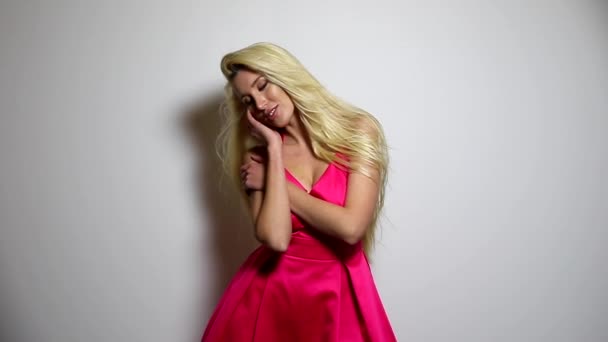 ピンクのドレスでセクシーな美人は、スタジオの背景にポーズします。スローモーション映像. — ストック動画