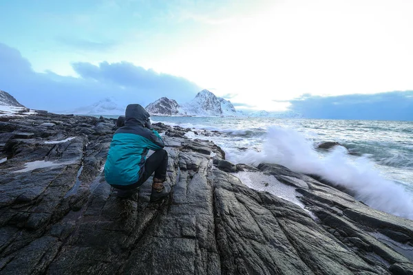 Fotografo di viaggio che fa foto in pietre antiche sulle rive del freddo mare norvegese di sera. Isole Lofoten. Bellissimo paesaggio norvegese . — Foto Stock