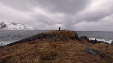 Seyahat fotoğrafçı akşam anda soğuk Norveç Denizi kıyısında antik taşlar resimleri yapıyor. Lofoten Adaları. Güzel Norveç manzara. HD ayak.