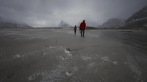 Группа фотографов-путешественников фотографирует на берегу холодного Норвежского моря в вечернее время. Лофотенские острова. Норвежский пейзаж. HD-кадры . — стоковое видео