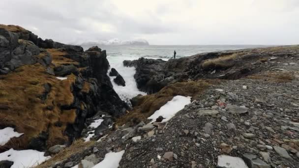 Reisefotograf beim Fotografieren in uralten Steinen an den Ufern des kalten norwegischen Meeres zur Abendzeit. Lofoten. schöne norwegische Landschaft. HD-Material. — Stockvideo