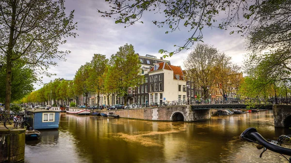 Os canais e aterros mais famosos da cidade de Amsterdã durante o pôr do sol. Vista geral da paisagem urbana e da arquitectura tradicional neerlandesa . — Fotografia de Stock