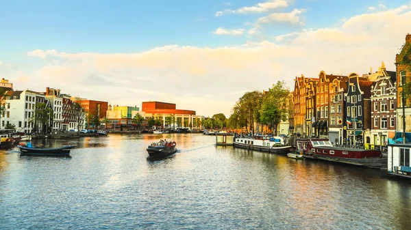 Die berühmtesten kanäle und dämme der stadt amsterdam bei untergang. Überblick über das Stadtbild und die traditionelle niederländische Architektur. — Stockfoto