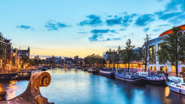 Os canais e aterros mais famosos da cidade de Amsterdã durante o pôr do sol. Vista geral da paisagem urbana e da arquitectura tradicional neerlandesa . — Fotografia de Stock